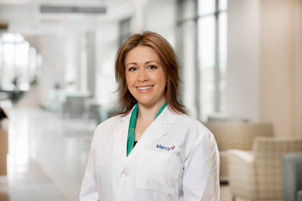 A head shot of Dr. Kalee Woody in a white lab coat with a Mercy logo.