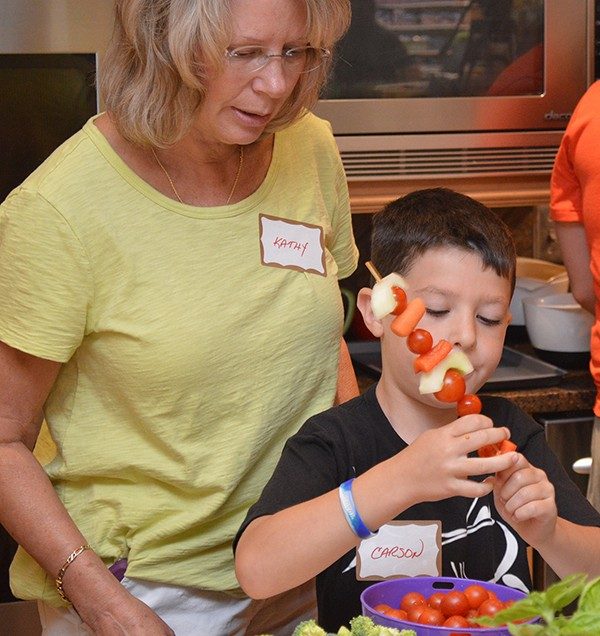 Kathy Stebe watches as Carson Weiss assembles a veggie kabob.