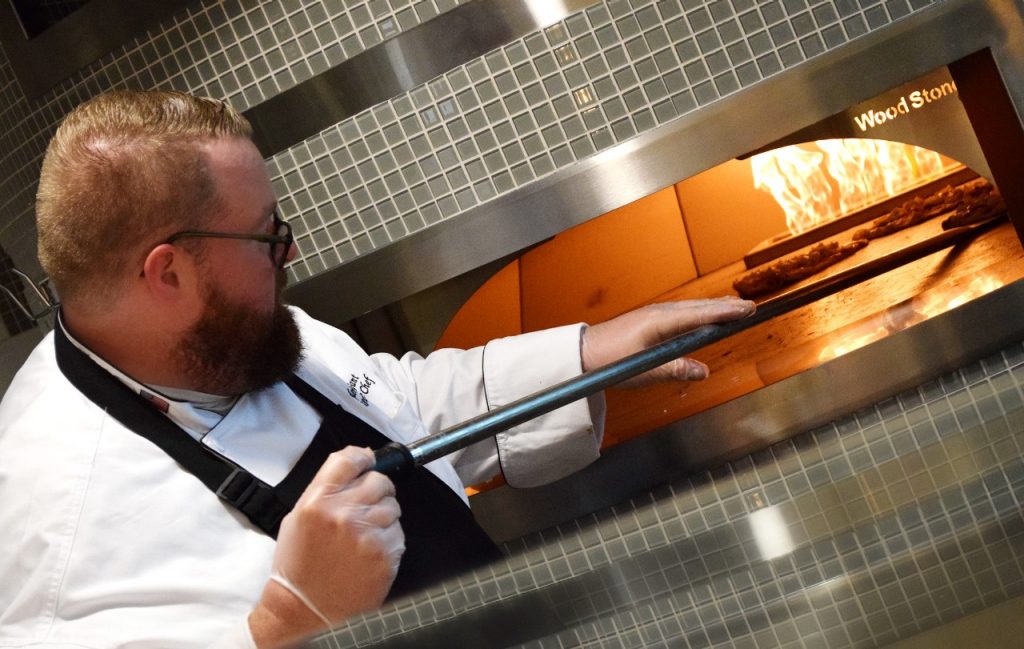 Mercy executive chef Tyler Gant removes a pizza from the new wood stone oven.