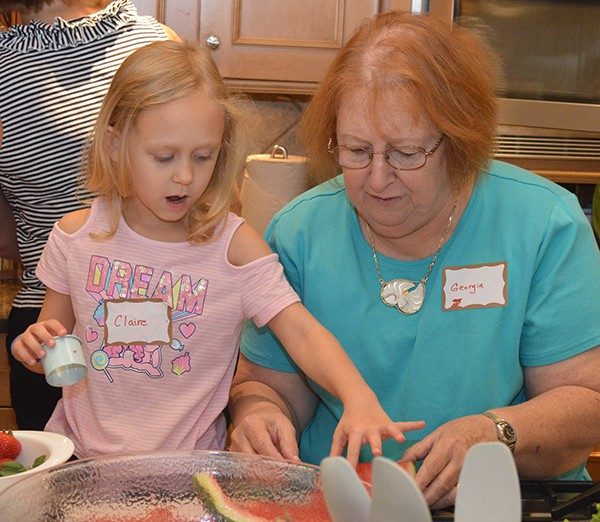 Claire Fyalka and Georgia Druen cut water melon wheels for the Frisbee fruit toss salad.