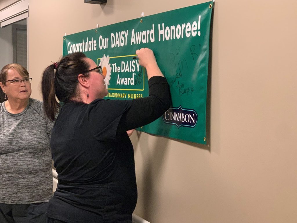 Mercy Hospital Joplin ICU nurse Erica Martin signs her name on the DAISY Award banner after being presented with her award.