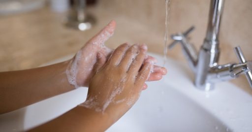 Cropped hand of girl washing hands at bathroom sink