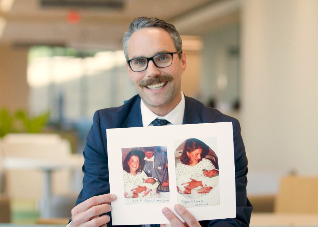 Bennett Geister holding photos of himself as a newborn with his mother.