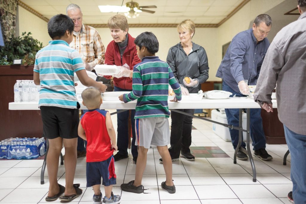 From left, Dale and Deb Bennett and Diana Hartung of Bland Chapel United Methodist Church offer boxed meals to a trio of boys as part of Mercy's outreach to the near-homeless at a motel in Rogers, Arkansas. (Permission granted from Catholic Health World, February 15, 2018
Copyright © 2018 by The Catholic Health Association of the United States.)
