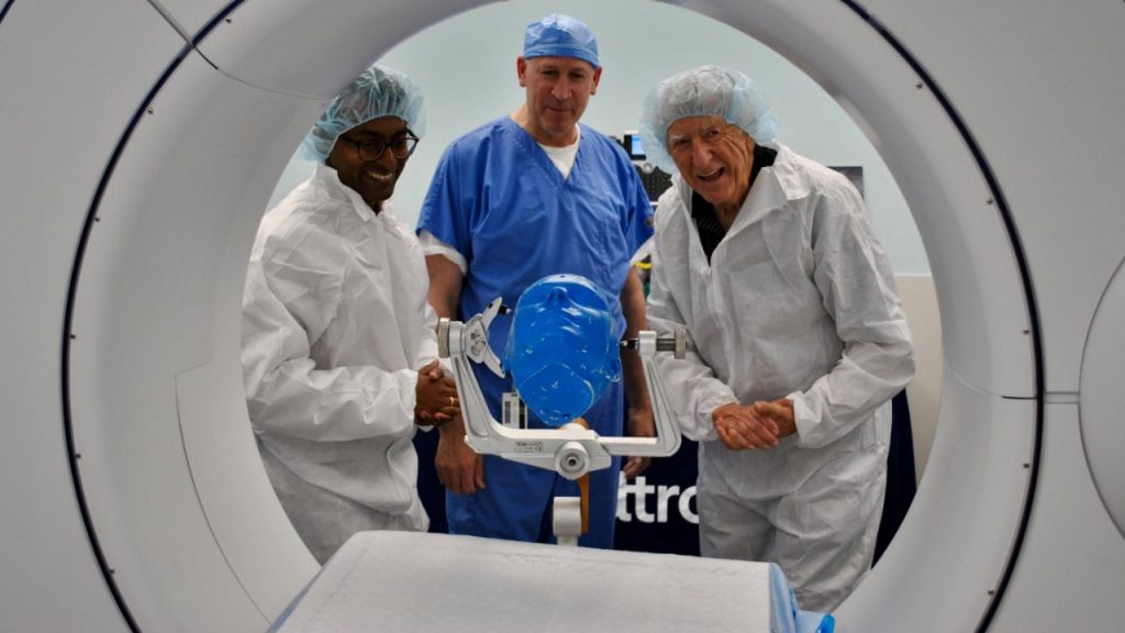 Herman Meinders and medical professionals wearing surgical clean room garb and watching a demonstration on a CT machine.
