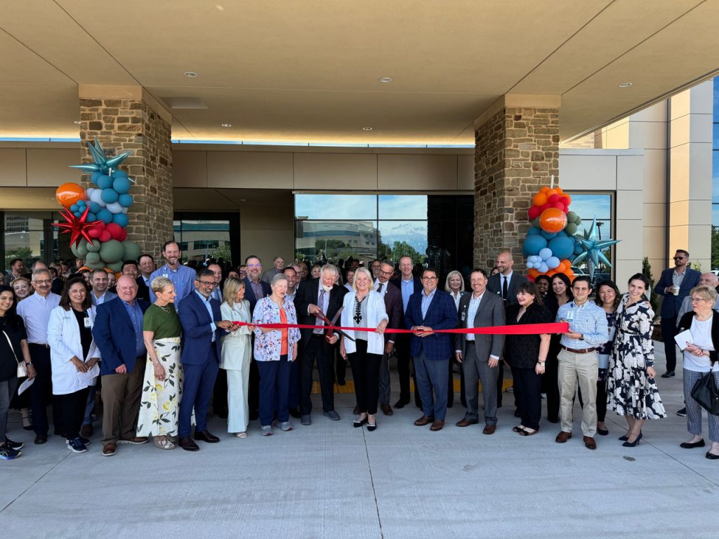 Dozens of people cut a ceremonial ribbon in front of the Kathryn Ann Meinders Digestive Health Institute.