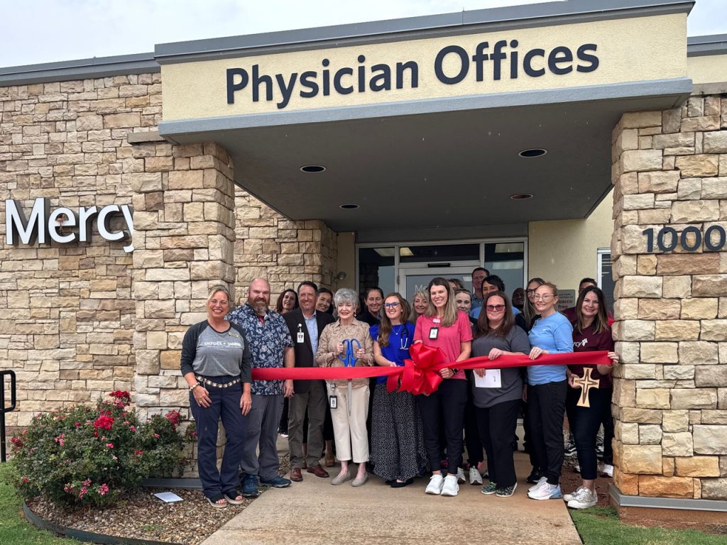 A group of Mercy caregivers and people from the Kingfisher community gather to cut a ceremonial ribbon in front of the Mercy primary care clinic.