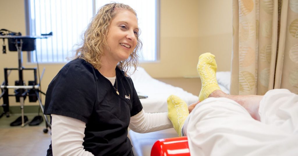 A physical therapist helps a patient during rehabilitation.