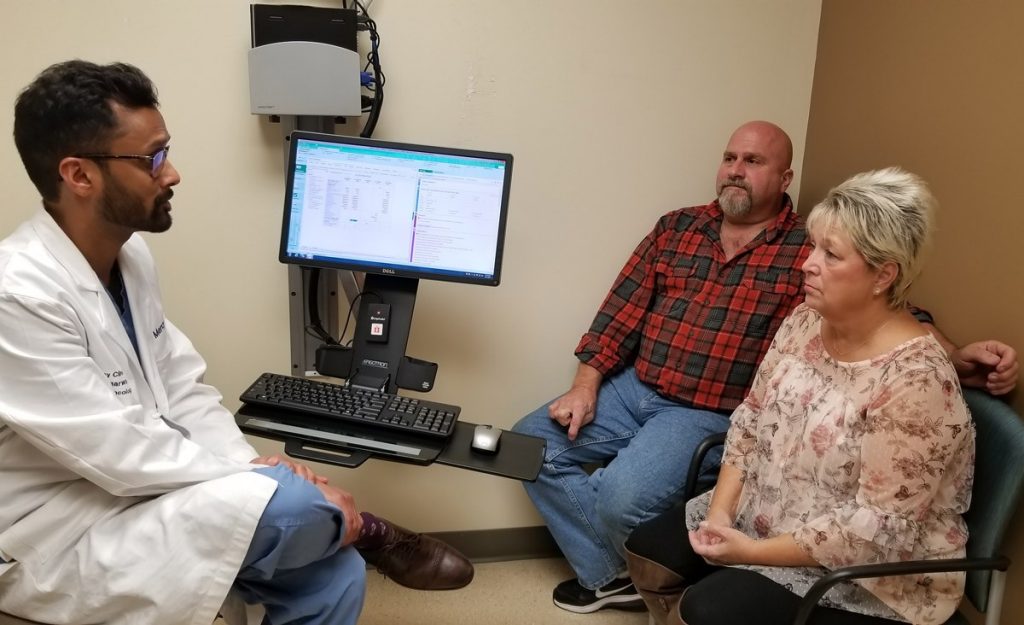 Dr. Gautum Agarwal speaks with a patient and her husband during a treatment follow-up appointment.