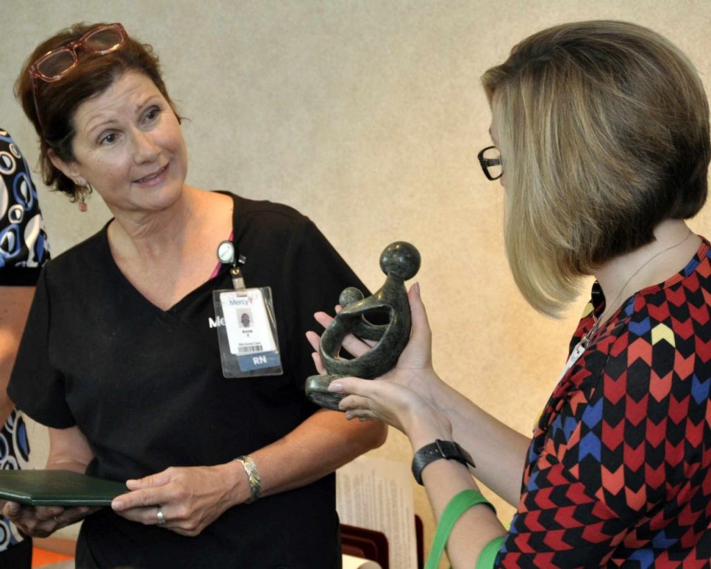 Corin Allen (right) presents Anne Tierney (left) with "The Healer's Touch" statue for earning the latest DAISY Award at Mercy Hospital South.