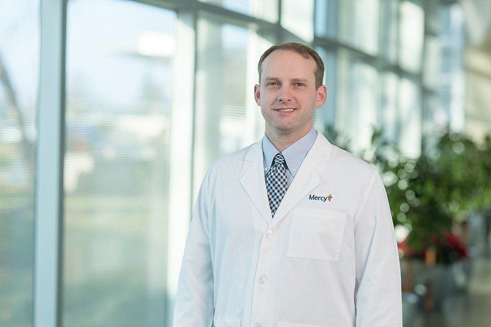 Dr. Mitch Wattles, orthopedic surgeon, in a white lab coat with a Mercy logo