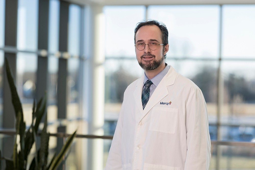 Dr. Tobias Mattei, neurosurgeon, in a white lab coat with a Mercy logo