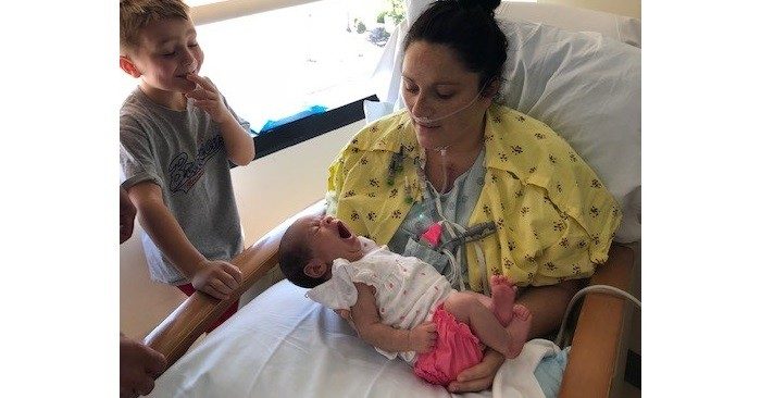 Janel Reeves holds her newborn daughter, Mela, while her son, Mason, looks on at Mercy Hospital South.