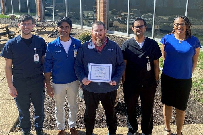 stroke medical director Dr. Marshall Kirsch in blue scrubs, chief medical officer Dr. Karthik Iyer in a blue quarter zip sweater and kahki pants, stroke program coordinator Josh Ennis, holding the Stroke Level 2 Center certificate, intensive care unit medical director Dr. Vikram Oke in black scrubs and emergency department medical director Dr. Rachel Edwards in a blue blouse and black skirt