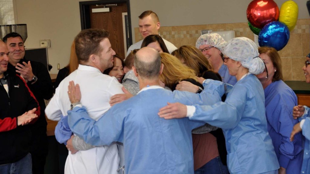 Jonathan Mitchell and his mother, Amy Alexander, are surrounded by Mercy Hospital South co-workers and Monroe County Ambulance District paramedics during a group hug.