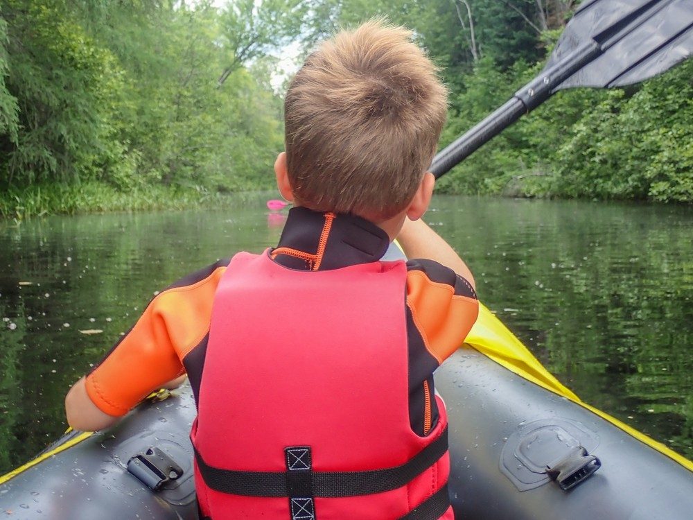 kid-behind-paddling-boat-lake-