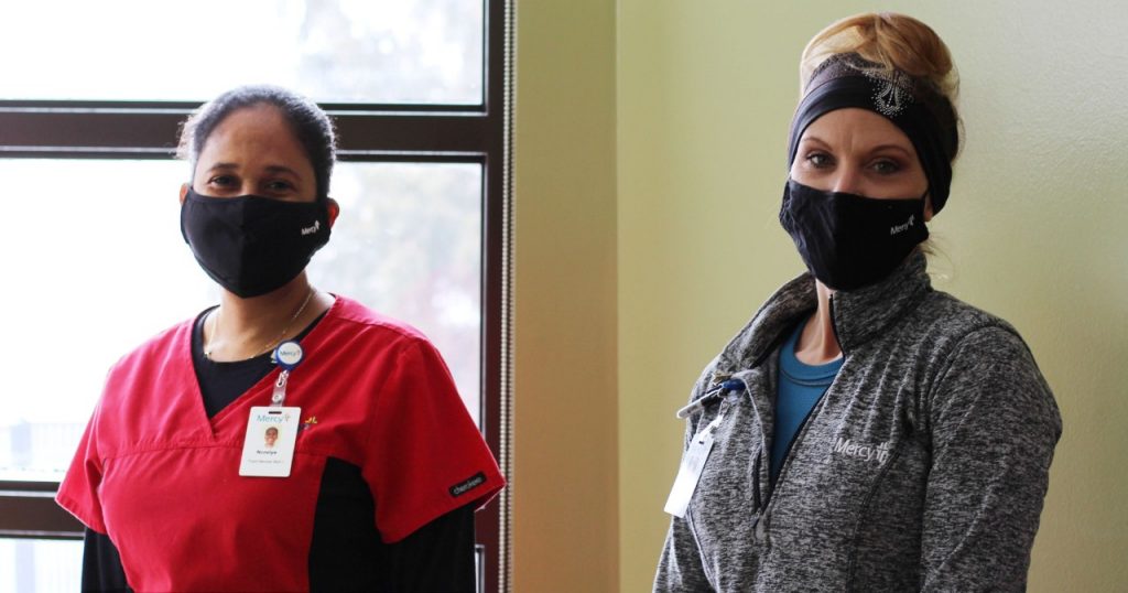 Co-workers Norelys Wood and Kristi Howell model the cloth masks made available to area businesses thanks to a grant from Toyota Motor Manufacturing, Missouri.