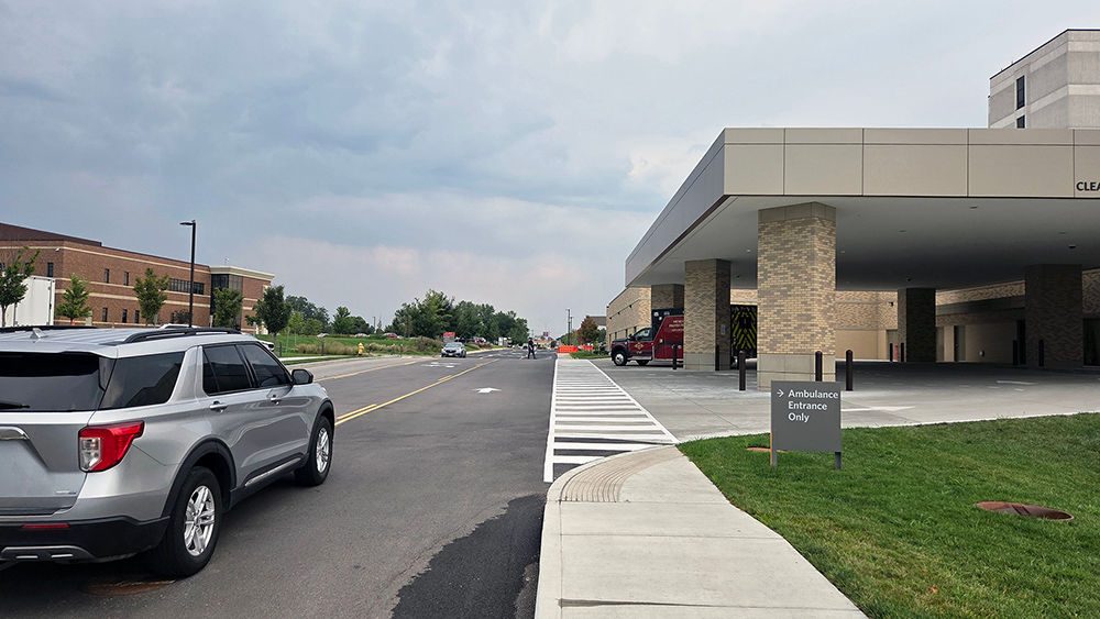 A car drives on the freshly paved and newly striped road heading from the south side of campus past the ambulance bay towards the front of Mercy Hospital South and the Sindelar Cancer Center.