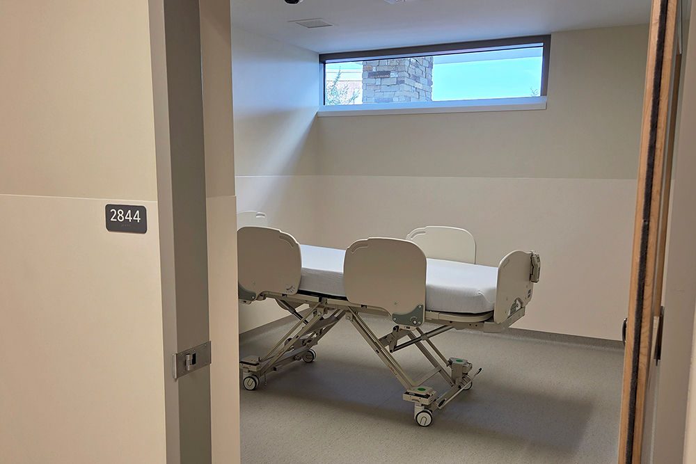 A patient care room with a bed and window across the top of the wall.