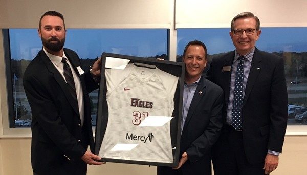 Mercy's Dr. Jesse Campbell (center) presents a framed jersey to OC Athletic Director David Lynn (left) and Vice President for Advancement Kent Allen (right).