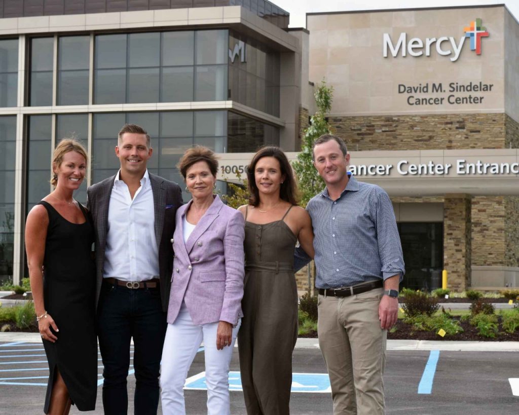 from left to right: Maria and James Sindelar, Sara Sindelar, and Lauren (Sindelar) and Coleman Sheehan pose in front of the David M. Sindelar Cancer Center at Mercy Hospital South.