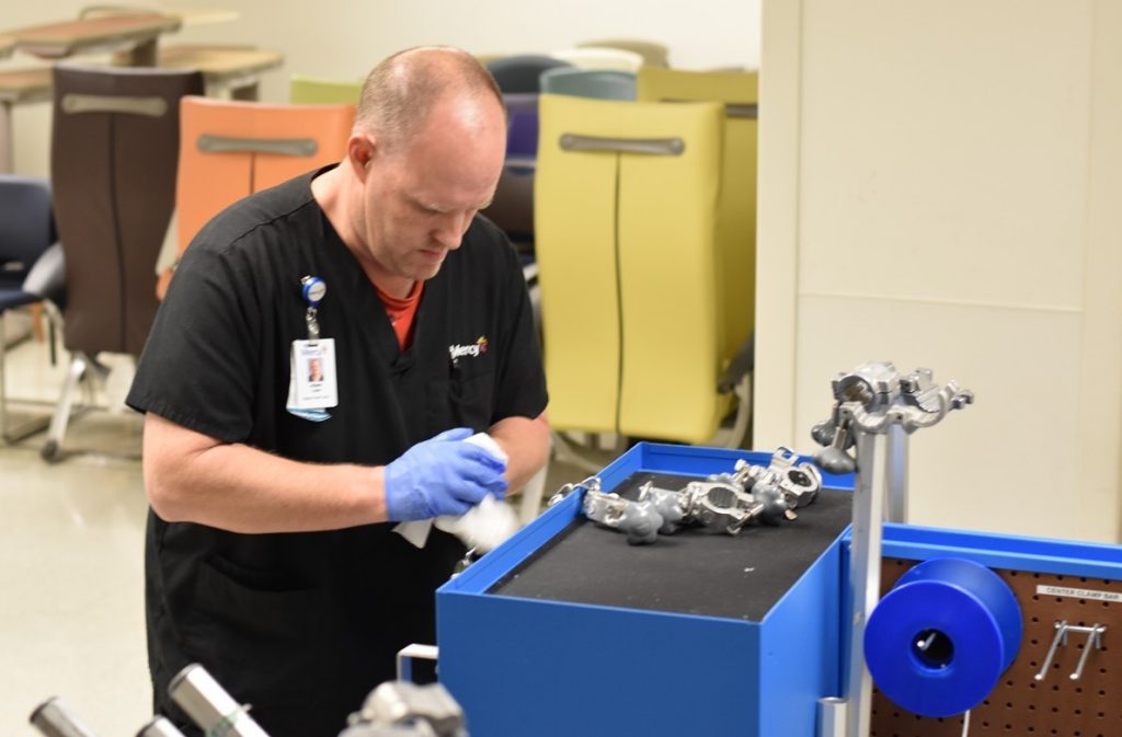 Adam Lare, supply chain technician at Mercy Hospital St. Louis, cleans and re-stocks supplies in a traction cart, which are mainly used to treat orthopedic injuries.
