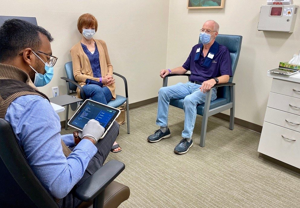 Dr. Cherian Karunapuzha adjusts the settings on Kevin Nicolin's device.