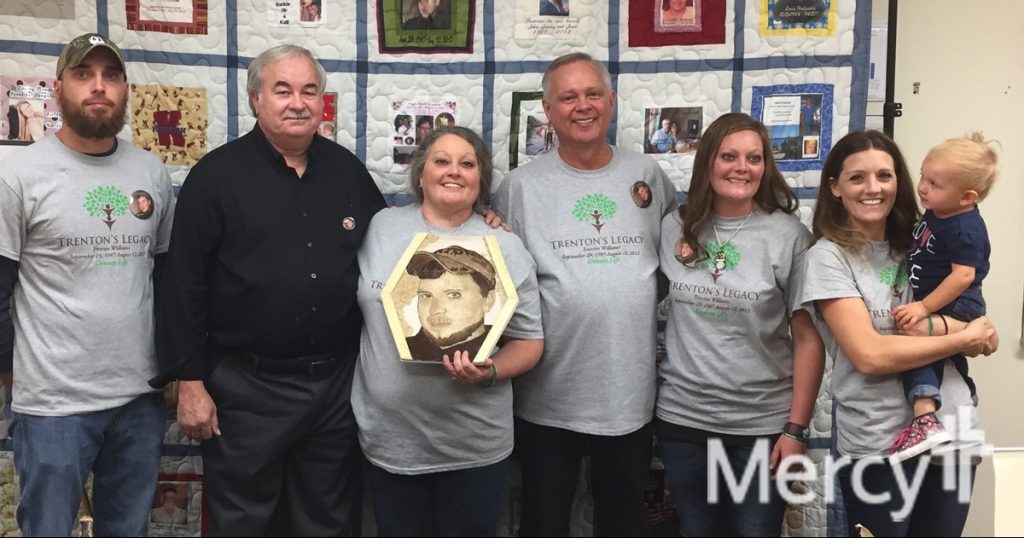 Jeri' Williams holding the floragraph honoring her son, Trenton, flanked by organ recipients Ken Howard, left, Keith Griffis, right, and Trenton's brother, sisters and niece.